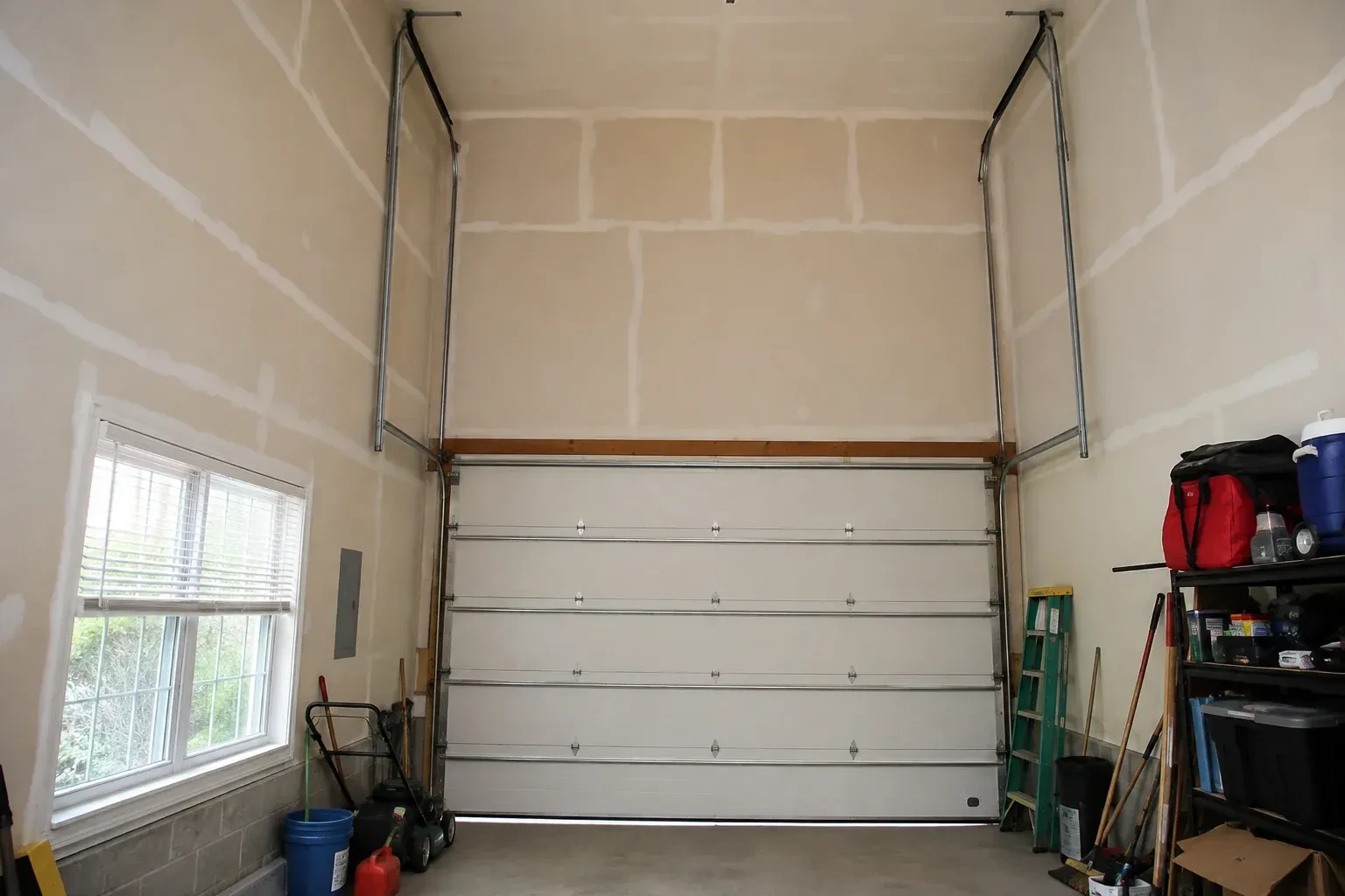 Tall garage interior with a sectional door and tracks extending into overhead space. — High-Lift Garage Door Conversion, London